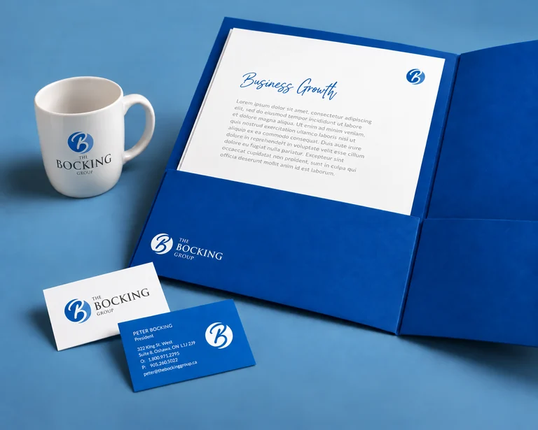 The Bocking Group branded mug, business cards and presentation folder together on a blue tabletop